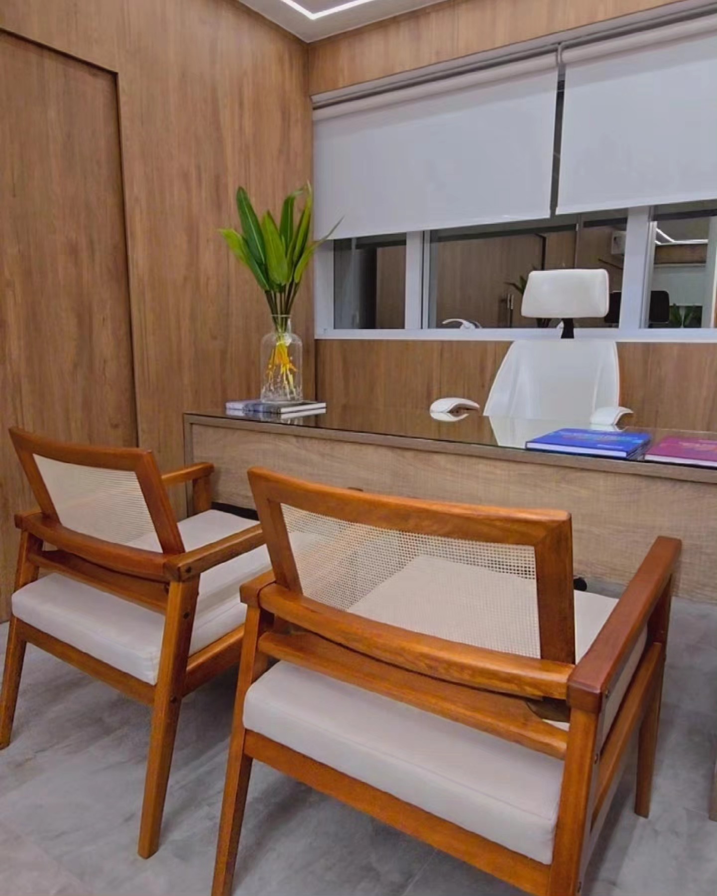 Espaço da CR Clinic com mesa, poltronas de madeira e paredes em tons naturais